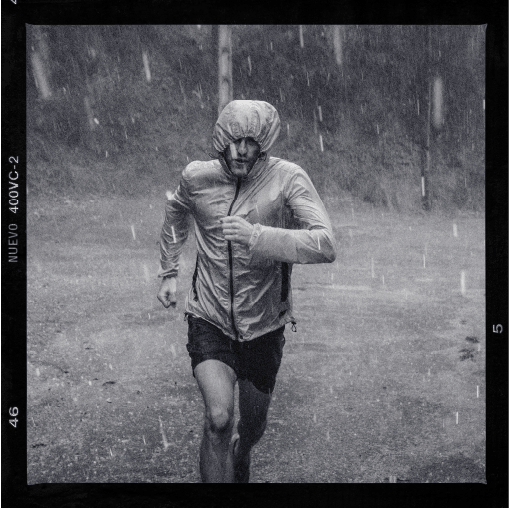 A man running in the rain with his hood up.